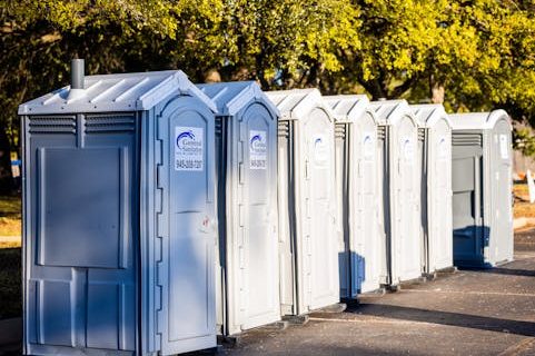 Home Multiple portable toilets aligned outdoors under trees, creating a sanitation solution.